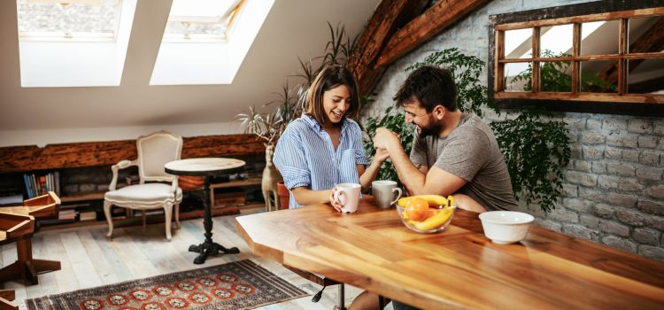Man and woman holding hands and drinking coffee at a table.