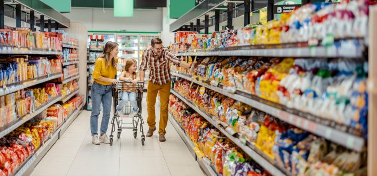 Man and woman pushing their daughter in a cart at the grocery store.