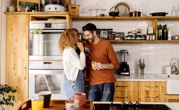 Couple drinking coffee and laughing in their kitchen.