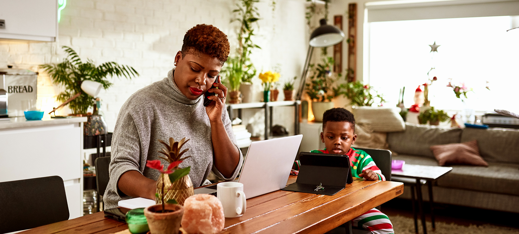 A mother talks on the phone at the dining table, while her
young son watches a tablet screen.