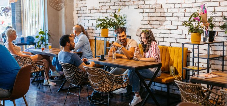 Two men and a woman sit at a table in a café drinking coffee.