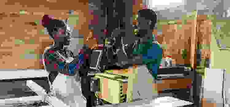 A man and woman use sign language in their workshop.