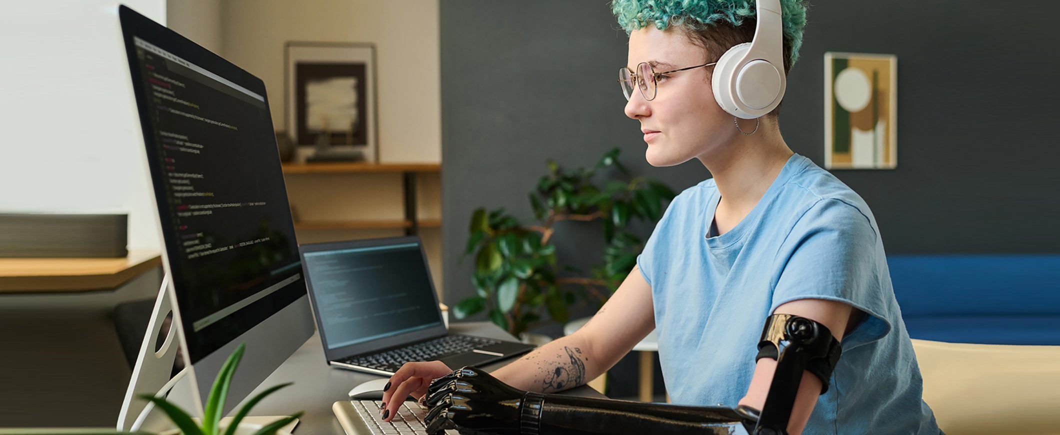 A young woman wearing a prosthetic device on her arm works at her computer.