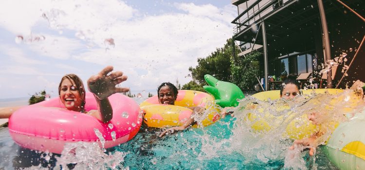 A group of friends have fun splashing around in pool floats.