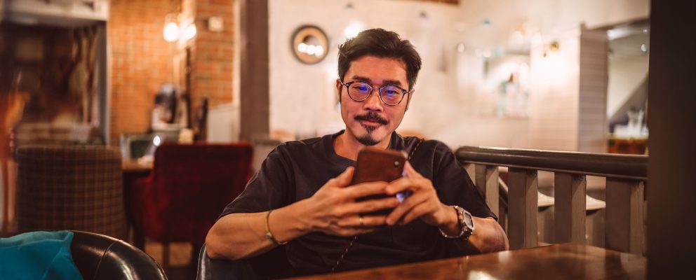 A young man sits and looks at his phone.