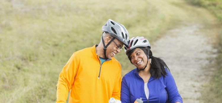 A couple riding bikes pauses to drink water on a trail.