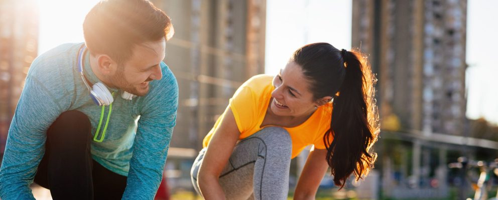 Couple smiling at each other while outside about to go on a run.