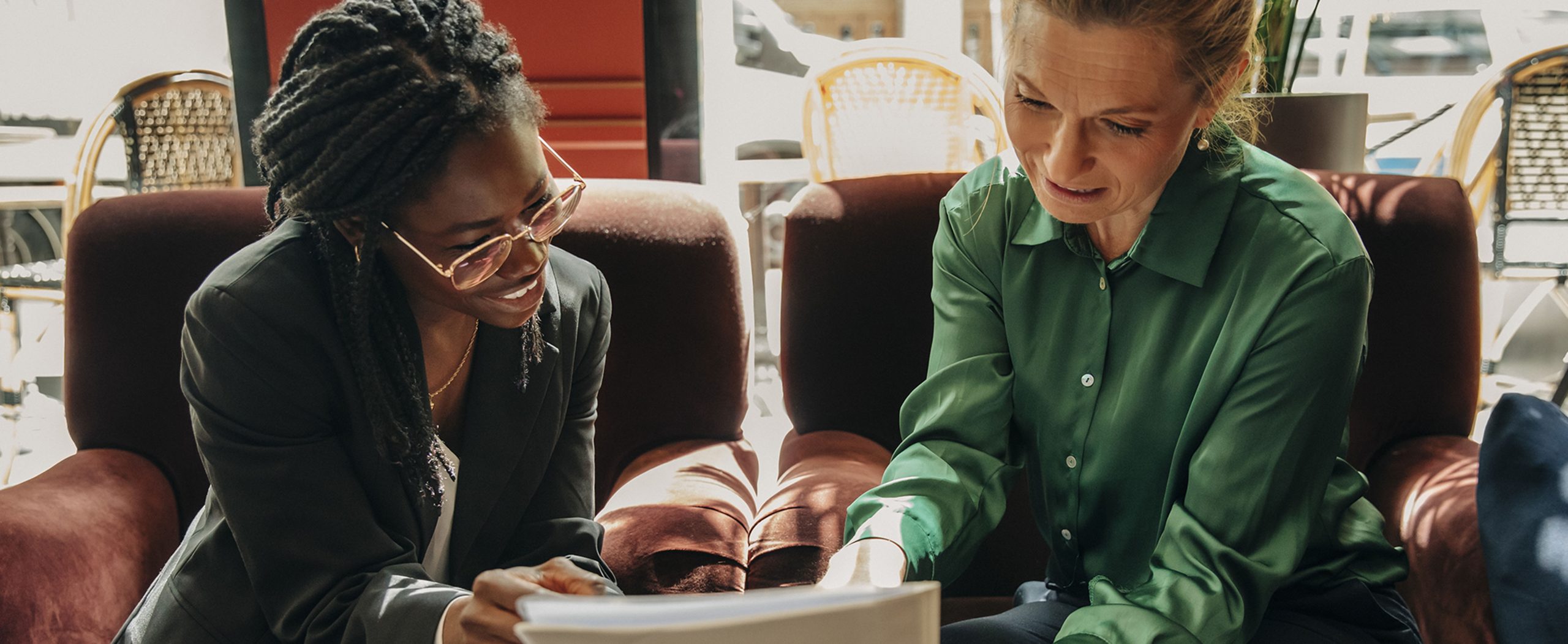Two women review paperwork together in a café