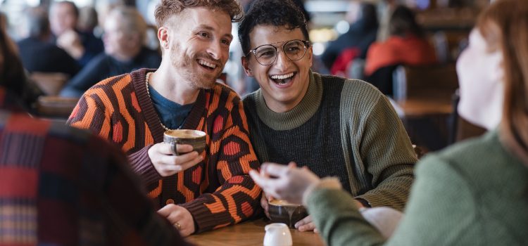 Two young men chat with friends in a crowded café.