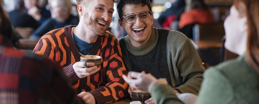 Two young men chat with friends in a crowded café.