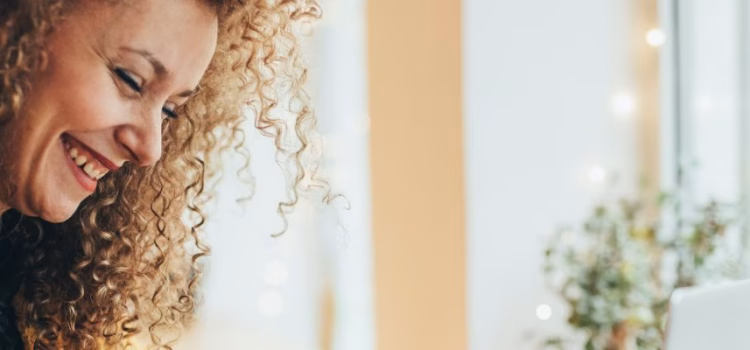 A close up of a woman reading her credit card to input the card number on her laptop keyboard.