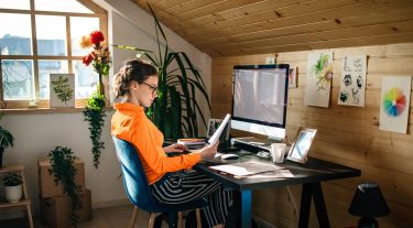 A woman looks at a piece of paper while working at her desk