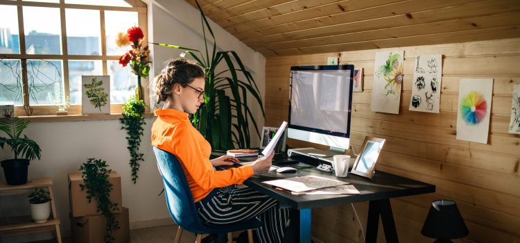 A woman looks at a piece of paper while working at her desk