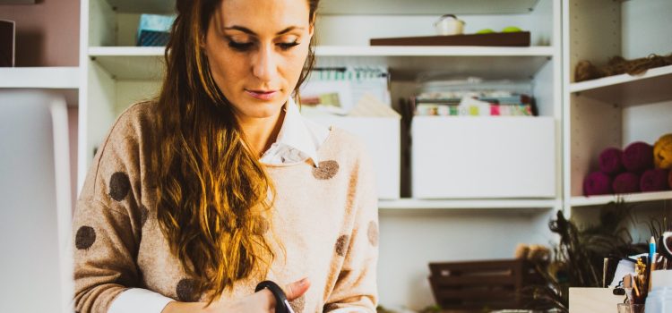 A woman sits at her desk cutting paper