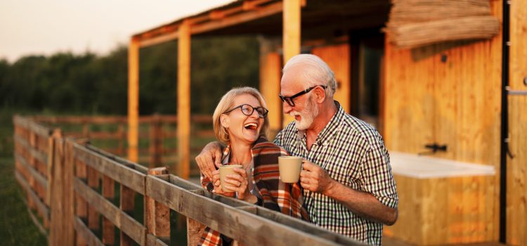 Older couple drinks coffee outside a barn.