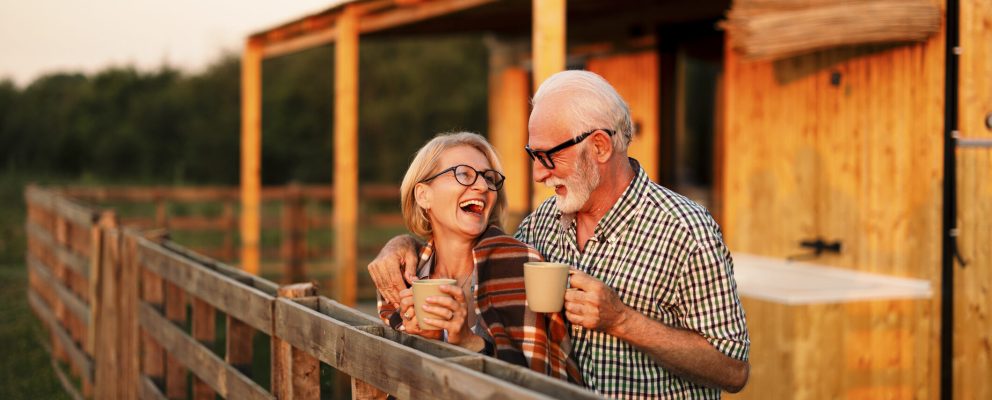 Older couple drinks coffee outside a barn.