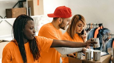 4 volunteers sort canned food into boxes