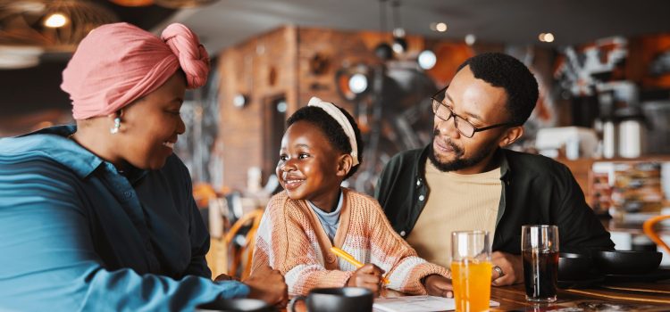 A family eats breakfast while the daughter smiles at her mother and father