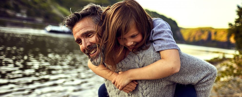 A father gives his daughter a piggyback ride.
