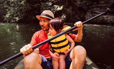 A man and a child in a canoe on a river.